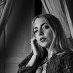 Chic black and white portrait featuring a woman with a nose ring and lace attire, delivering a sophisticated look indoors.